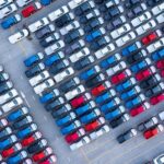 Aerial view new cars for sale stock lot row, New Cars dealer inventory import export business logistic global. | TechSplicit aerial view new cars